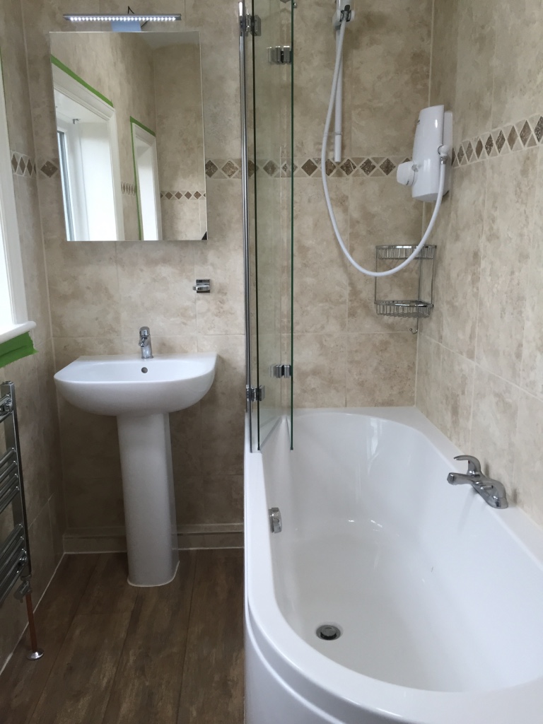 New bathroom with curved bath & travertine tiles